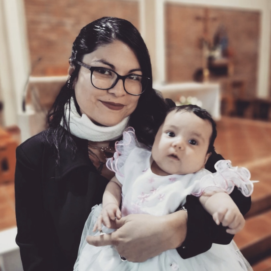 Zelda sonriendo con una bebé en brazos